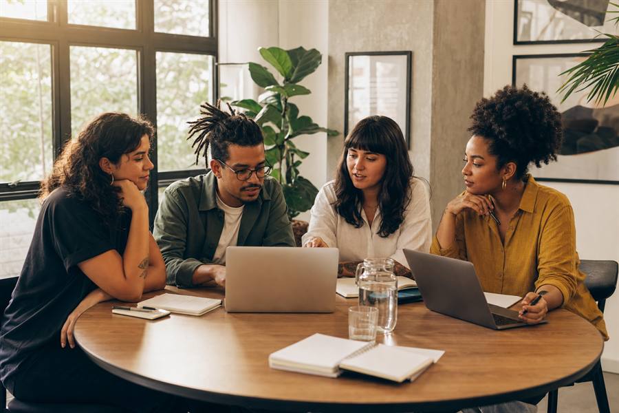 Reuniao de equipe editorial em mesa redonda com laptops e cadernos